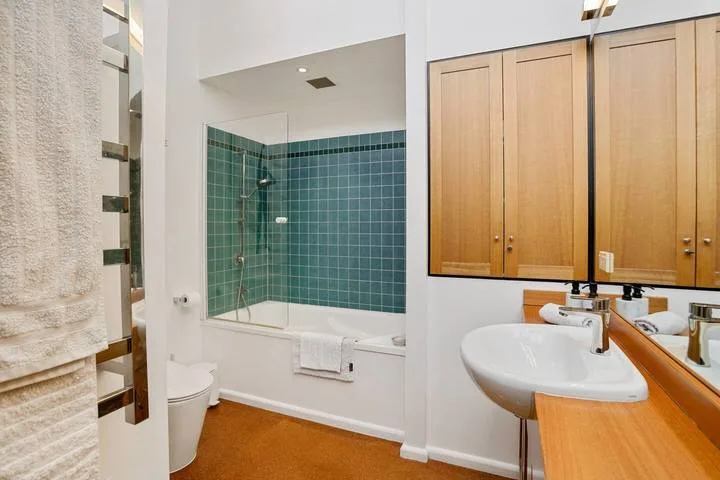 A bathroom with a bathtub, glass shower screen, and sink.