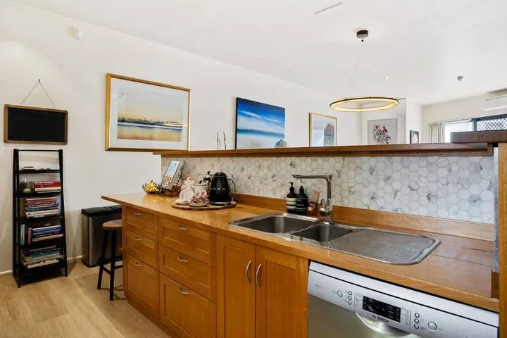 A kitchen with wooden cabinets, a long countertop, and a double sink.