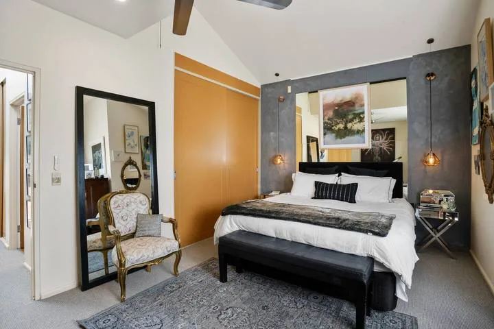 A bedroom with a large bed, bedside lamps, and a mirror.