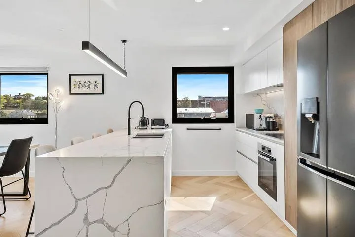 A bright modern kitchen with a large island and stainless steel appliances.