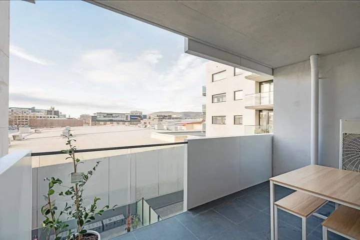 A covered balcony with a small potted plant and views of nearby buildings.