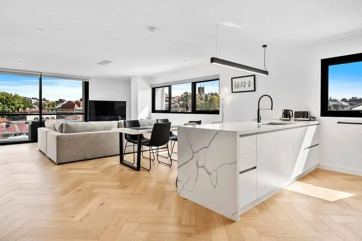 An open-plan living room and kitchen with a large island and dining seating.
