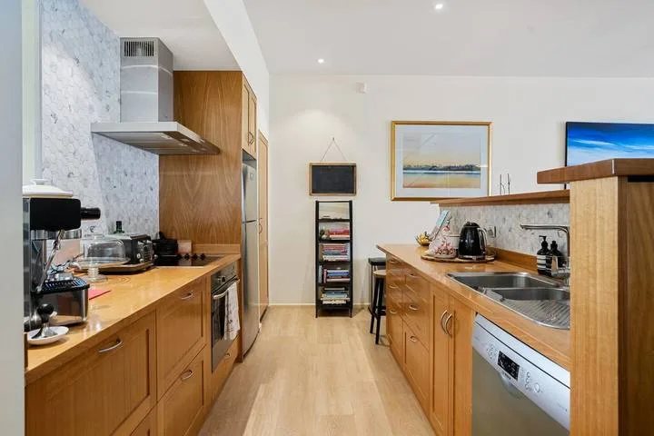 A kitchen with wooden cabinetry, long countertops, and stainless steel appliances.