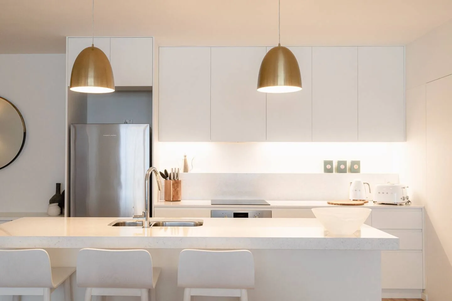 A modern kitchen with white cabinetry, a refrigerator, and a large island.