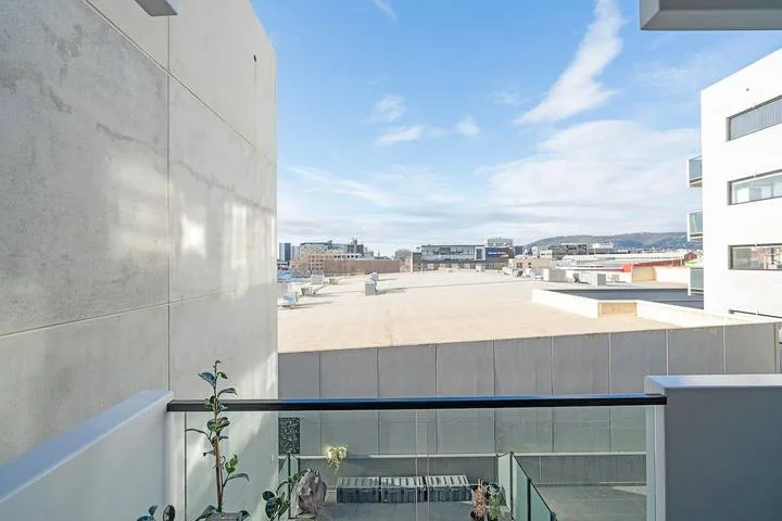 A rooftop terrace overlooks nearby buildings beneath a partly cloudy sky.