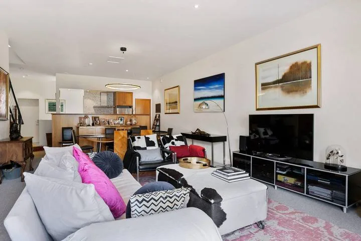 An open-plan living room with seating, a television, and a dining area.