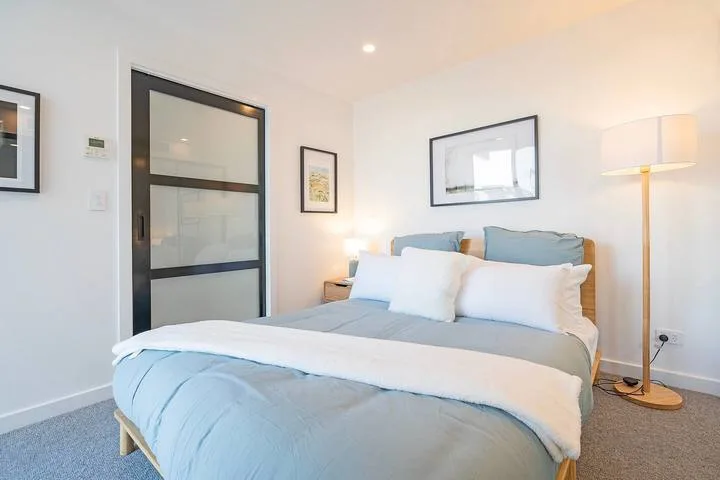 A bedroom with a neatly made bed and framed artwork on the walls.