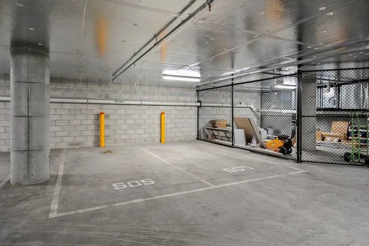 An underground parking area with marked spaces and a fenced storage section.