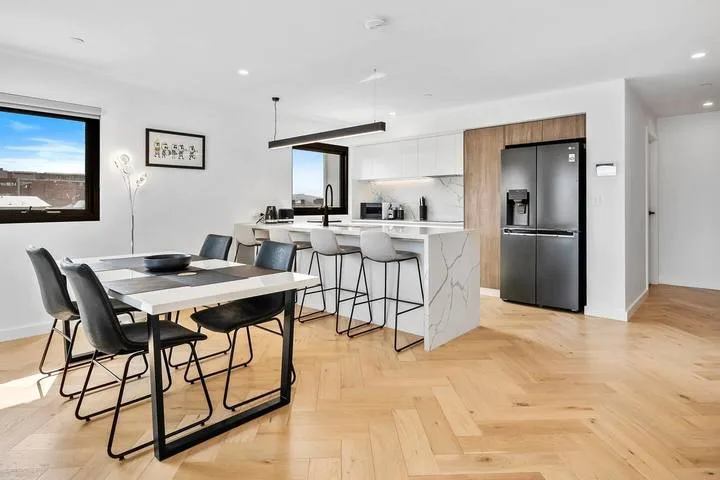 A bright open-plan kitchen and dining area with a table and counter seating.