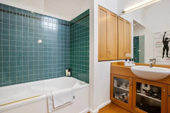 A bathroom with a bathtub and a wooden vanity topped by a sink.