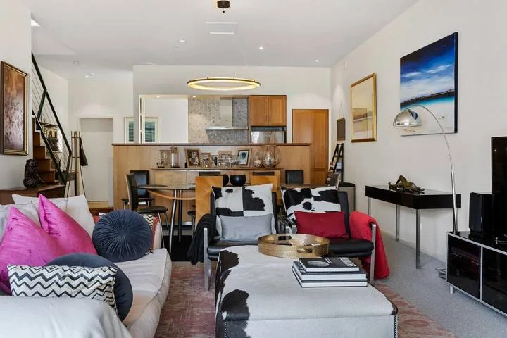 A living room with seating, a coffee table, and a kitchen area in the background.