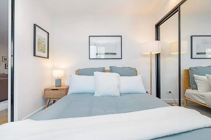 A bedroom with a neatly made bed and framed artwork on the walls.