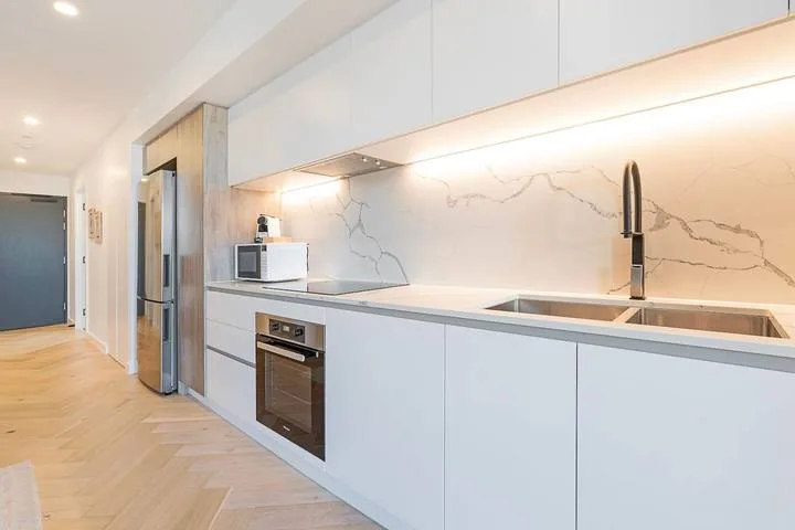 A modern kitchen with pale cabinets, a countertop, and a built-in oven.