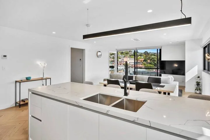 A bright open-plan kitchen with a large island and dining area beside wide windows.