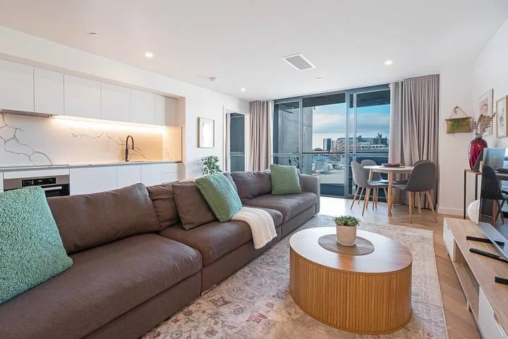A bright living room with a large sectional sofa and a dining area by the windows.