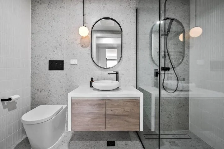 A modern bathroom with a vanity, wall mirror, and glass shower.