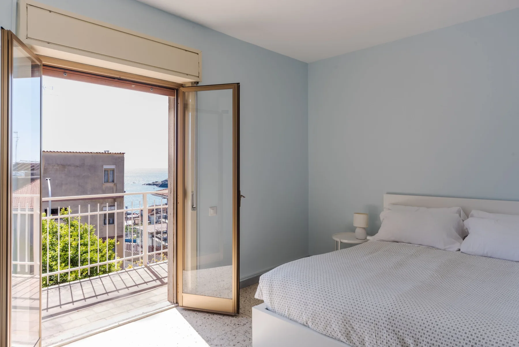 Un dormitorio con la puerta del balcón abierta y vistas al mar.