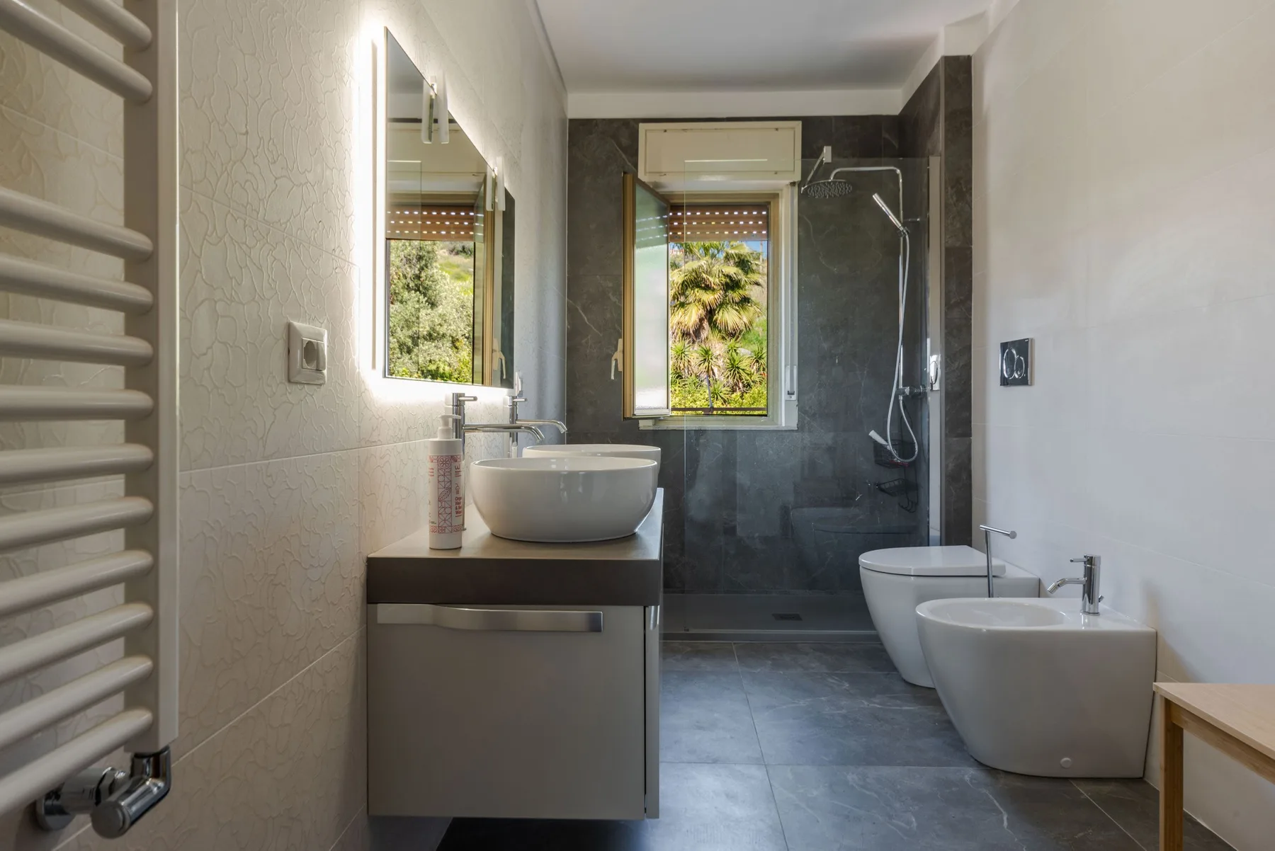 Un baño moderno con lavabo, inodoro y zona de ducha con mampara de vidrio.