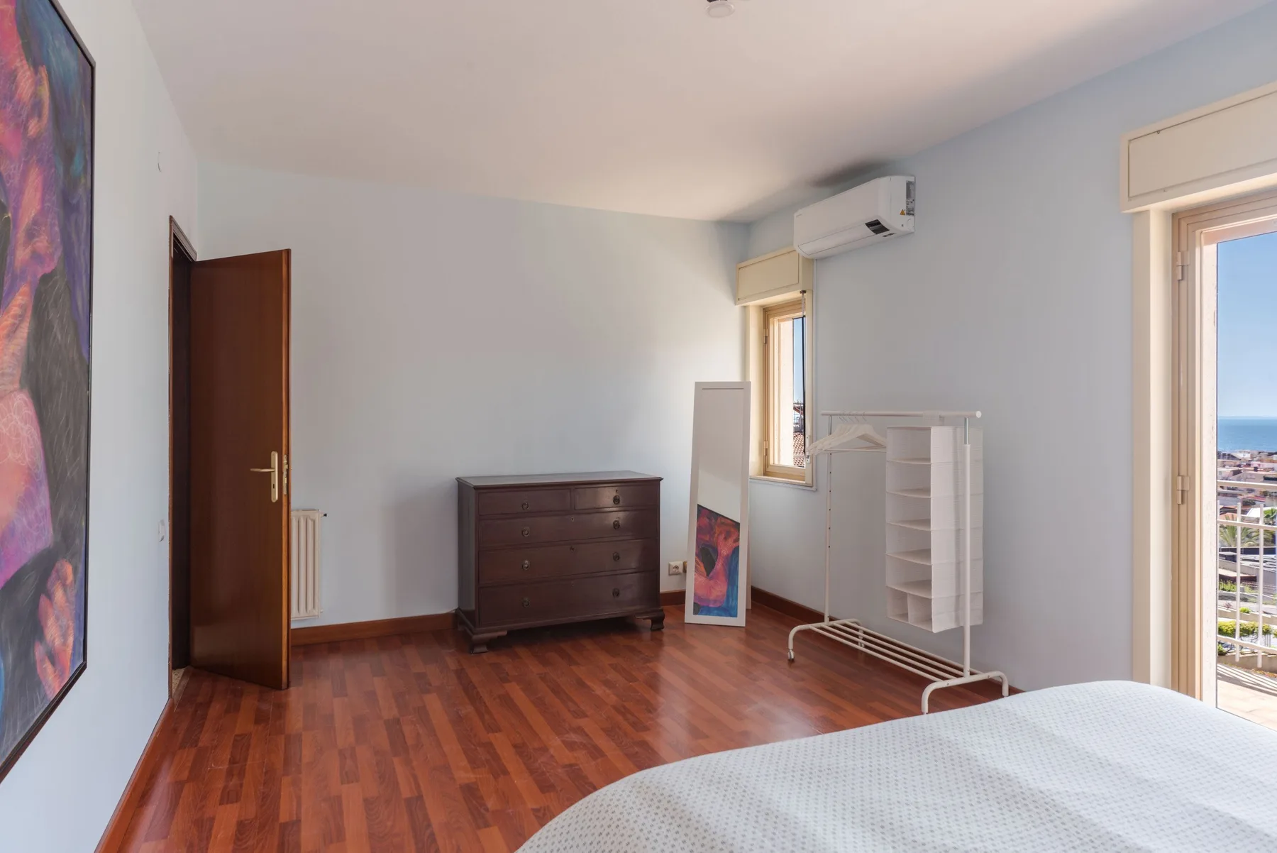 Un dormitorio con suelo de madera, una cómoda y una cama.
