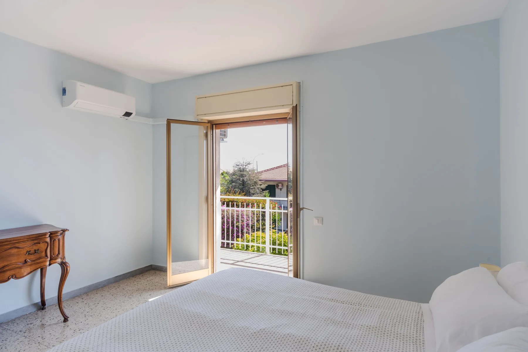 Un dormitorio con la puerta del balcón abierta y una cama en primer plano.