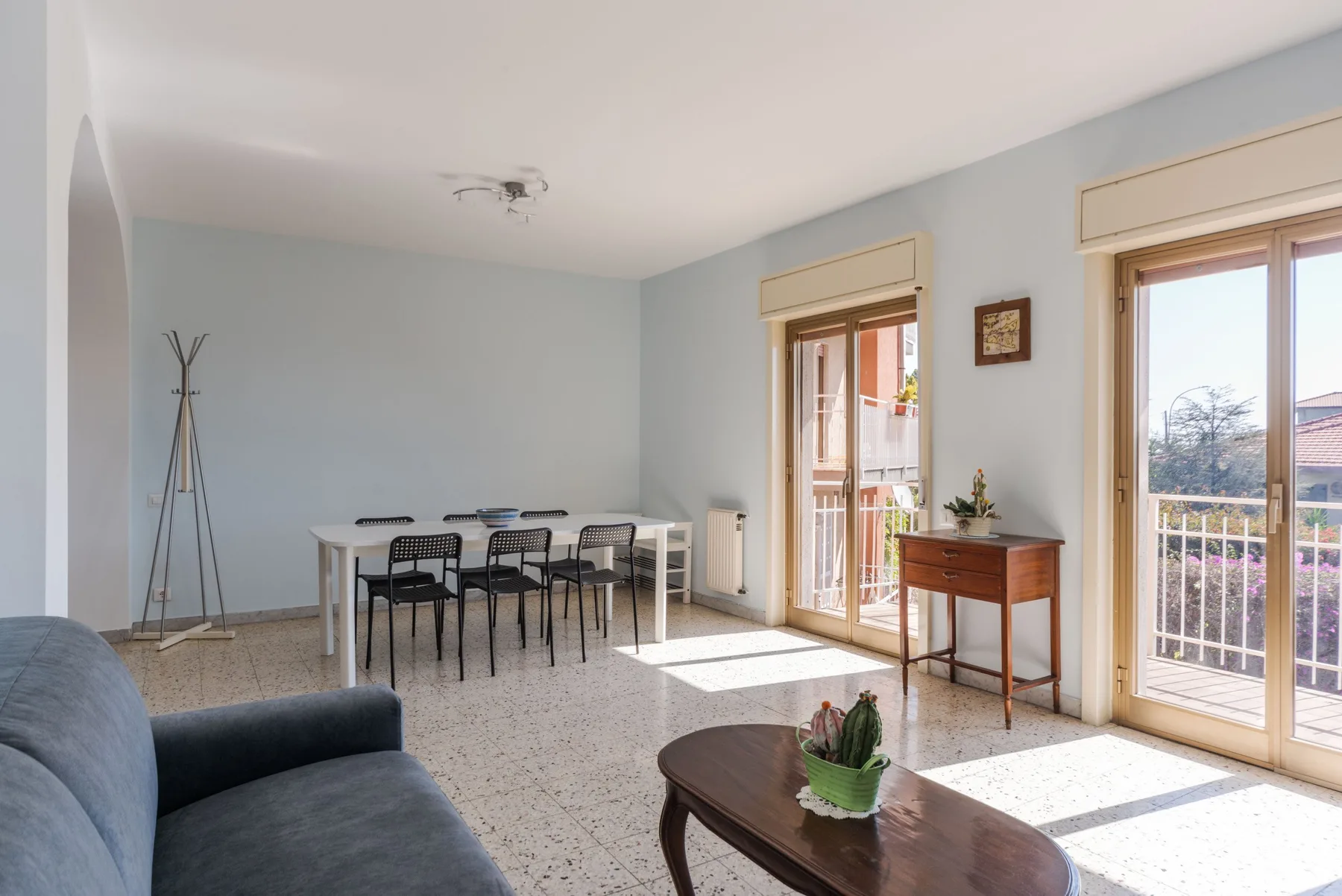 Una luminosa sala de estar y comedor con mesa, asientos y puertas acristaladas.