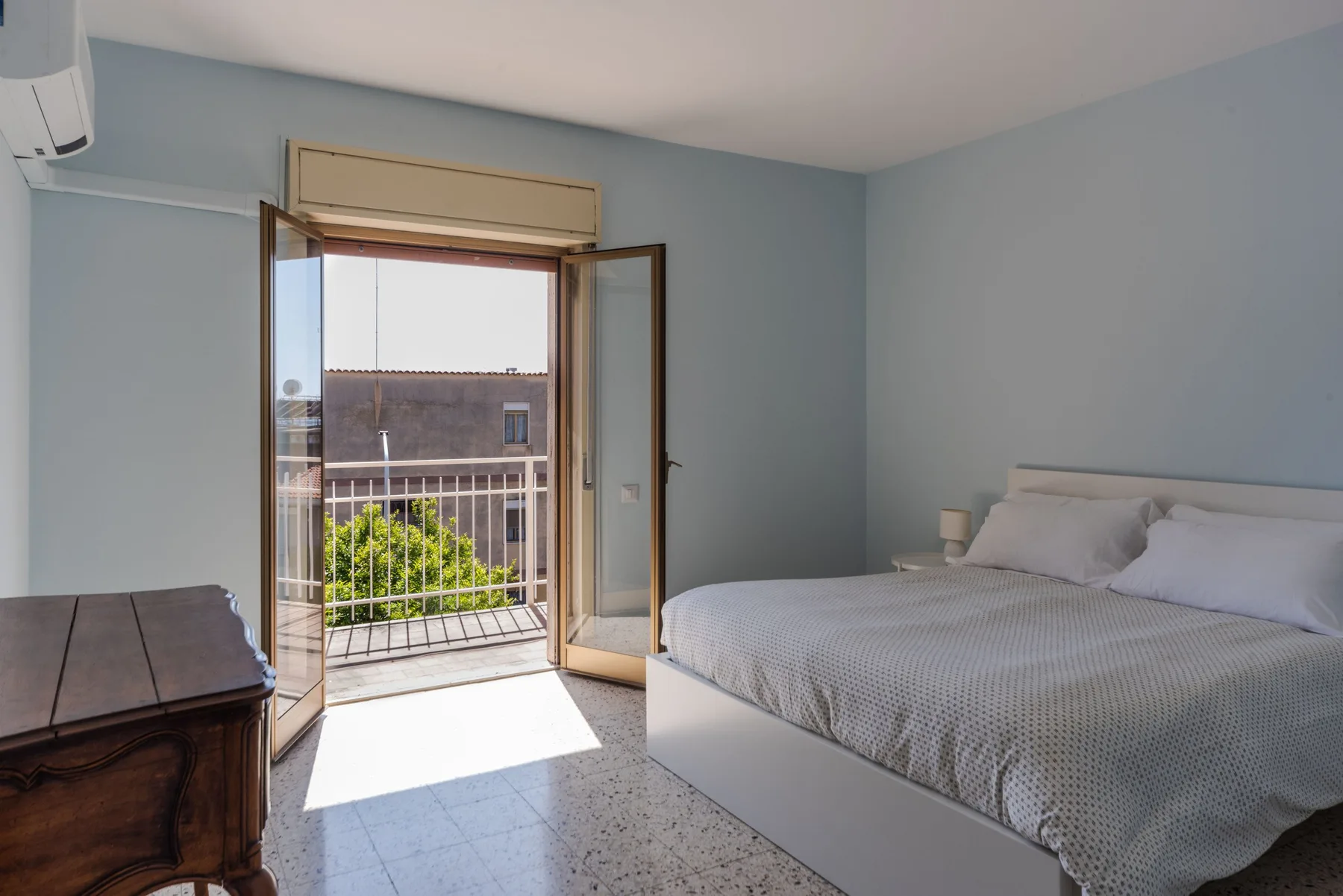 Un dormitorio con una cama junto a puertas abiertas que dan a un balcón.