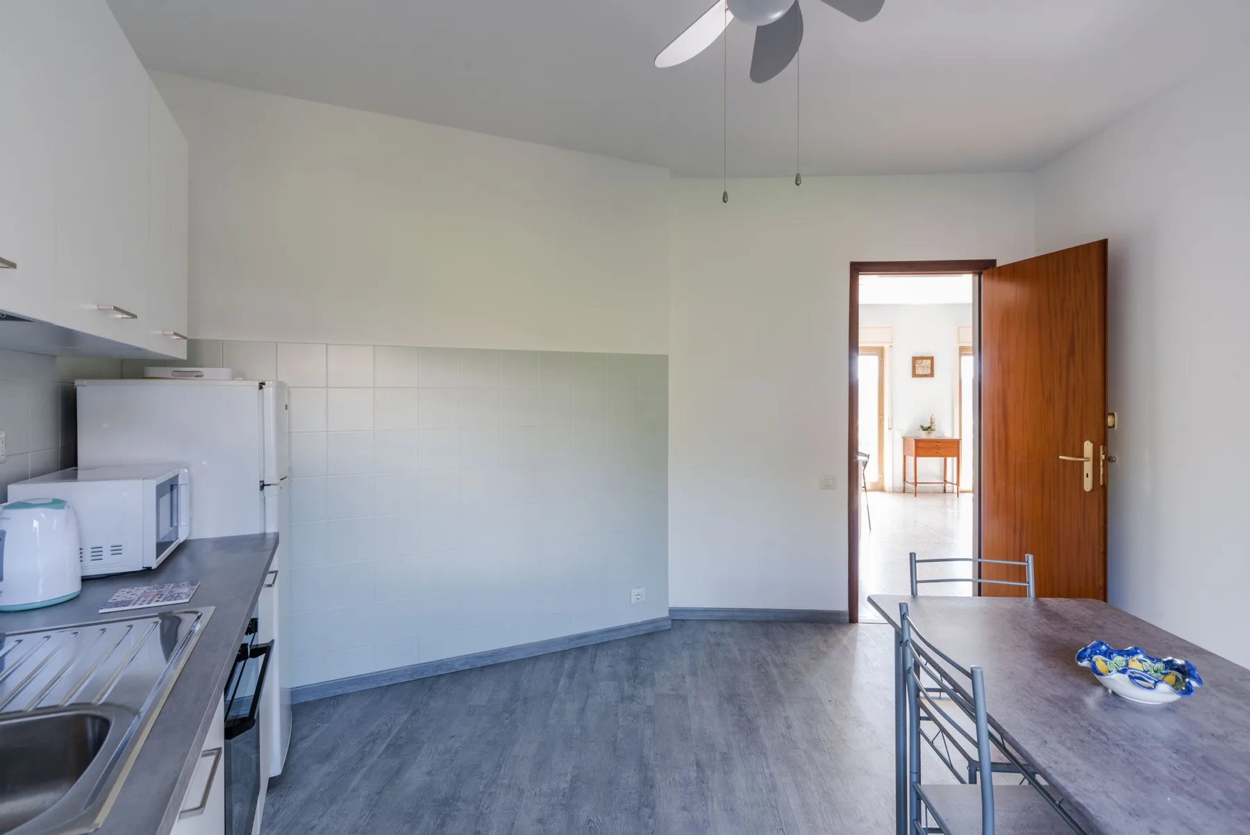 Una cocina y comedor con suelo gris, encimeras y una mesa.