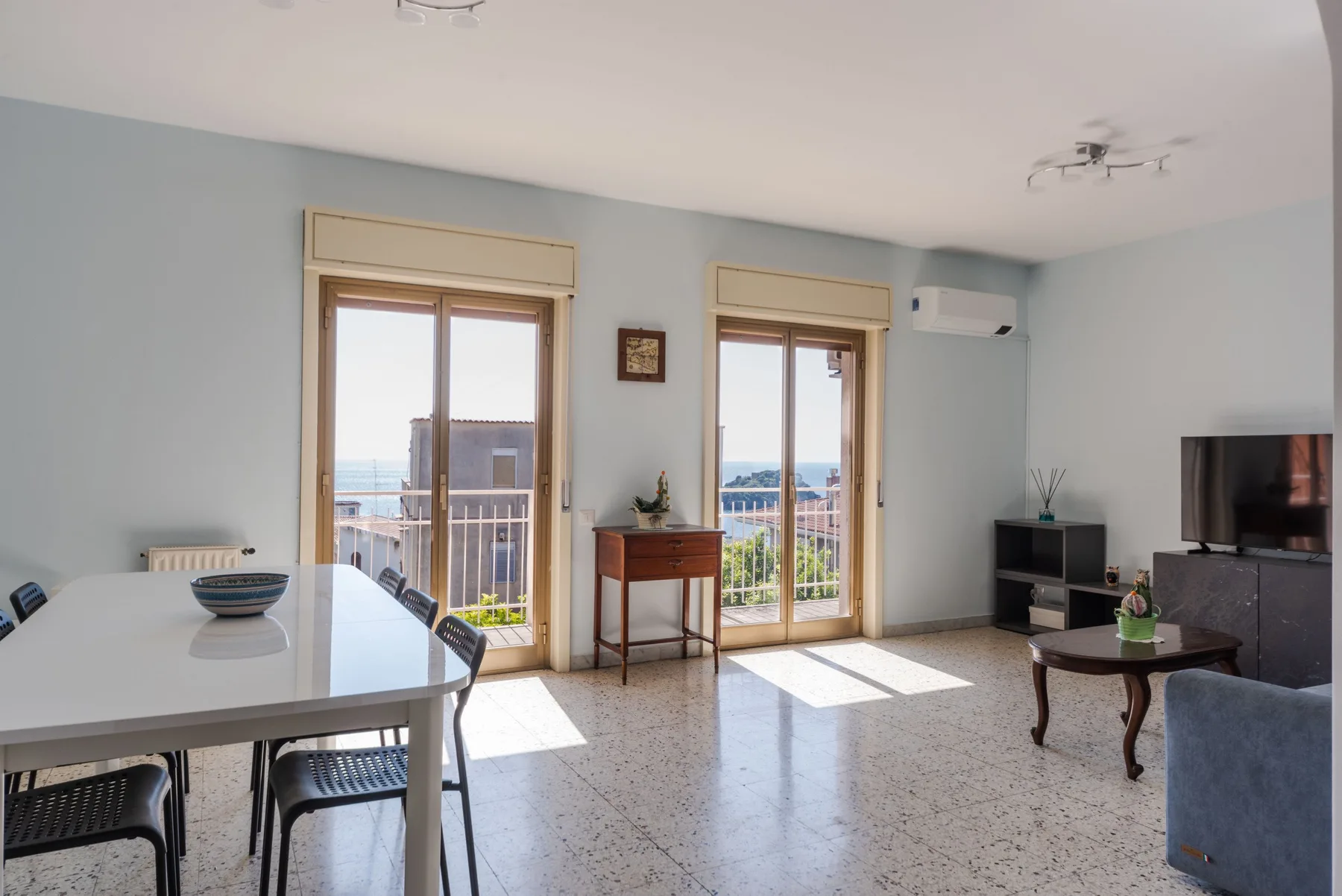 Una sala-comedor luminosa da a un balcón a través de puertas de vidrio altas.