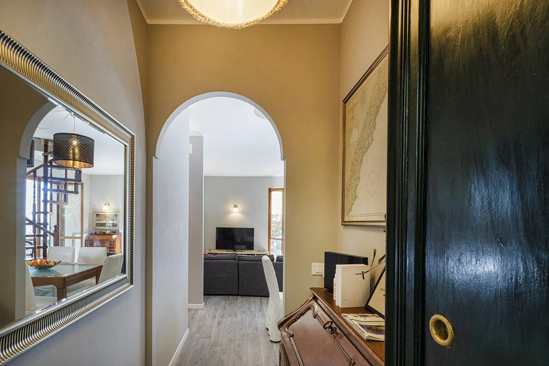 An arched hallway opens into a living area with a television.