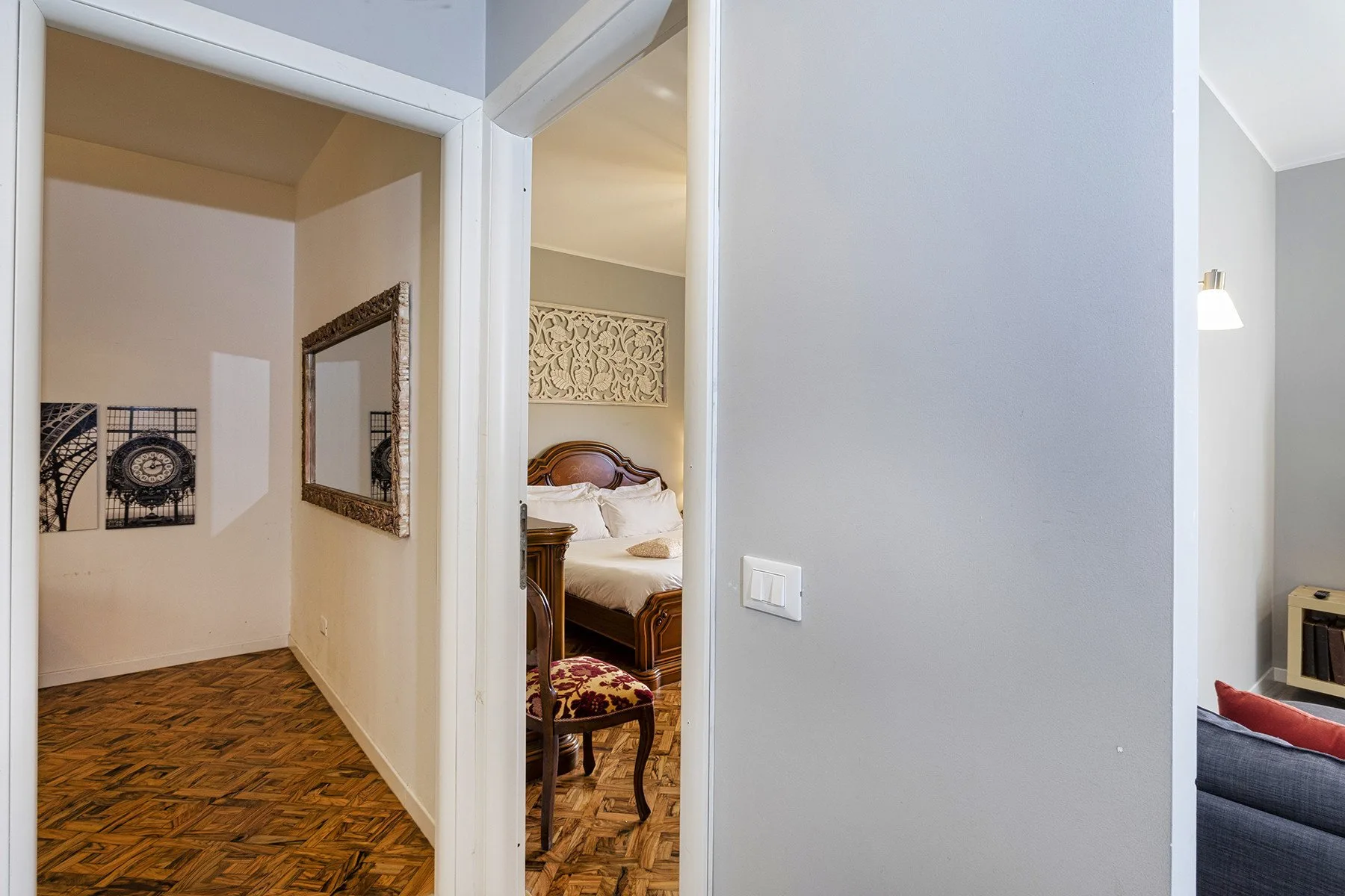 A hallway opens onto a bedroom, with framed artwork on the walls.