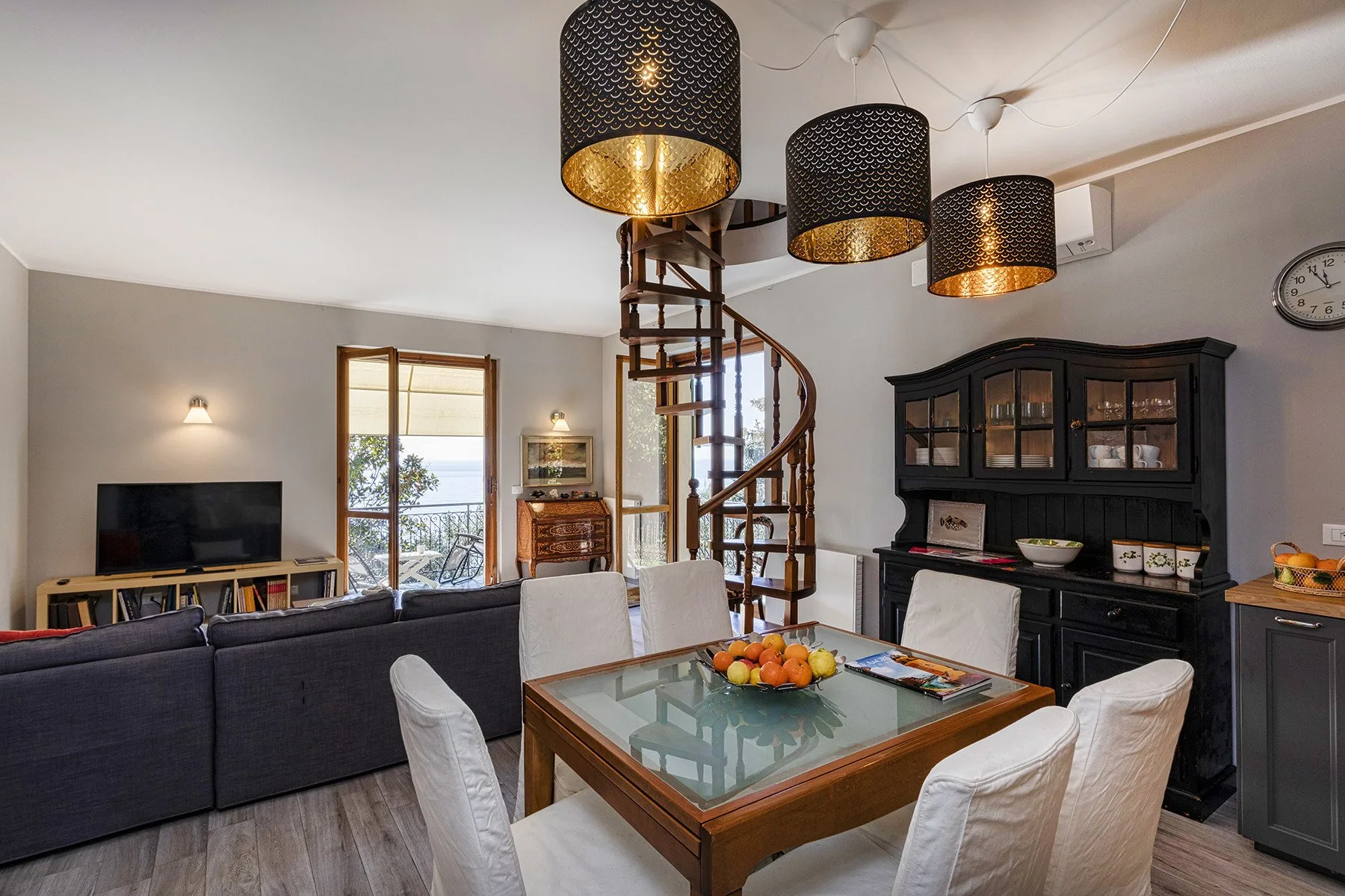 A living and dining area with a spiral staircase and a glass-top table.