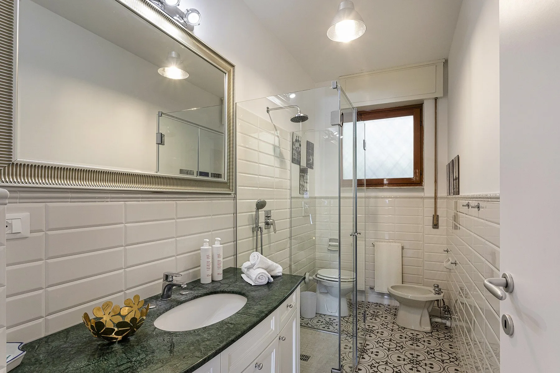 A tiled bathroom with a sink, mirror, and glass shower.