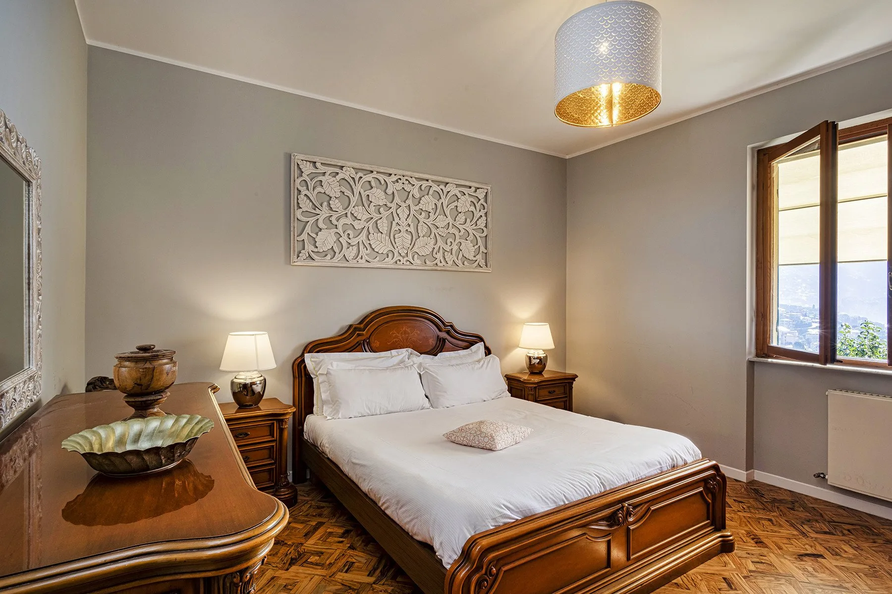 A bedroom with a wooden bed, white bedding, and a window.