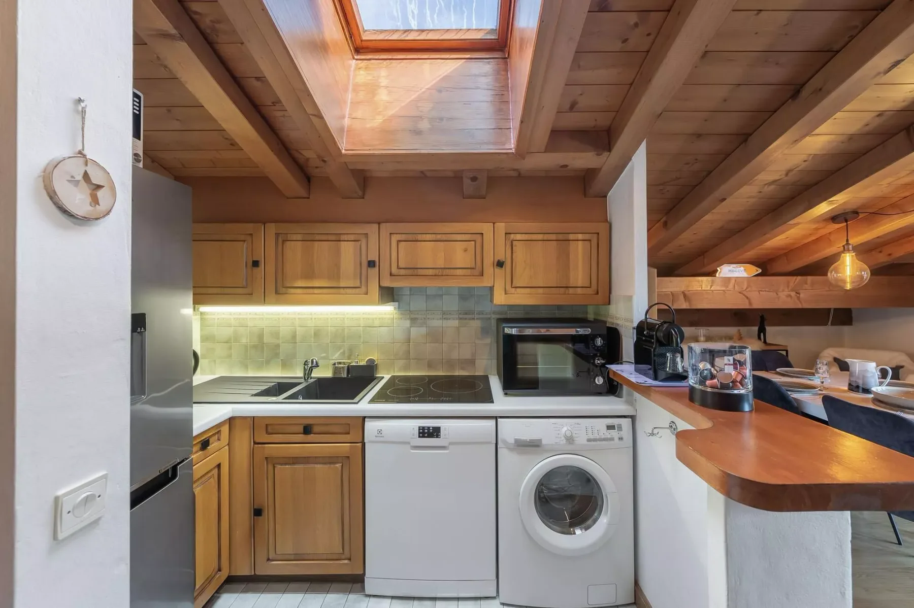 Una cocina compacta con gabinetes de madera, una claraboya y una encimera.