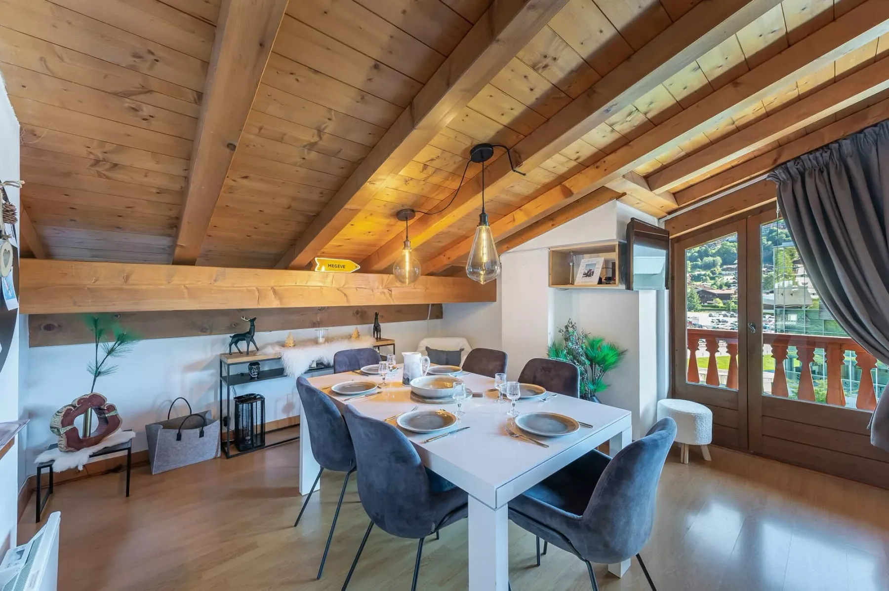 Un comedor con la mesa puesta bajo un techo inclinado de madera.