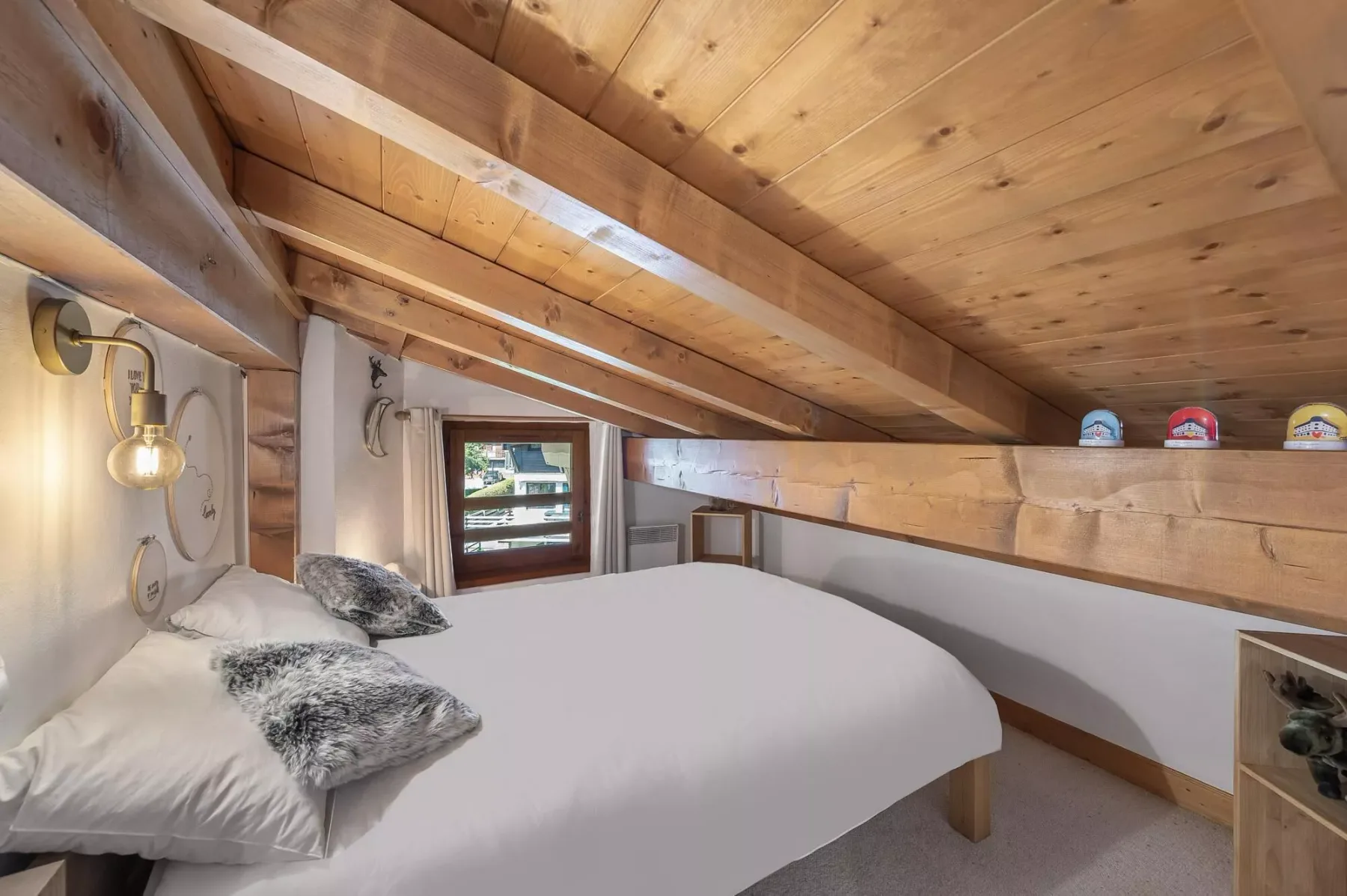 A bedroom with a bed beneath a sloped wooden ceiling.