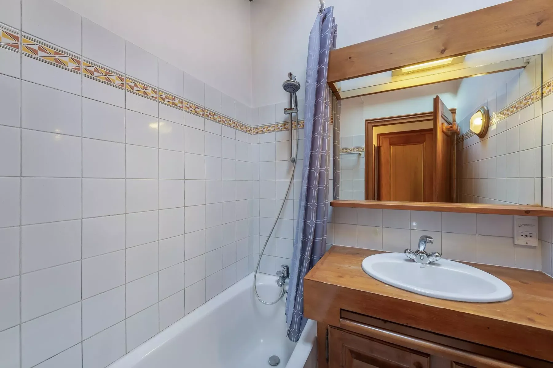 A tiled bathroom with a bathtub, shower, and wooden vanity.