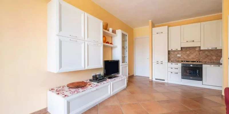 A bright kitchen with white cabinets, a countertop, and tiled flooring.