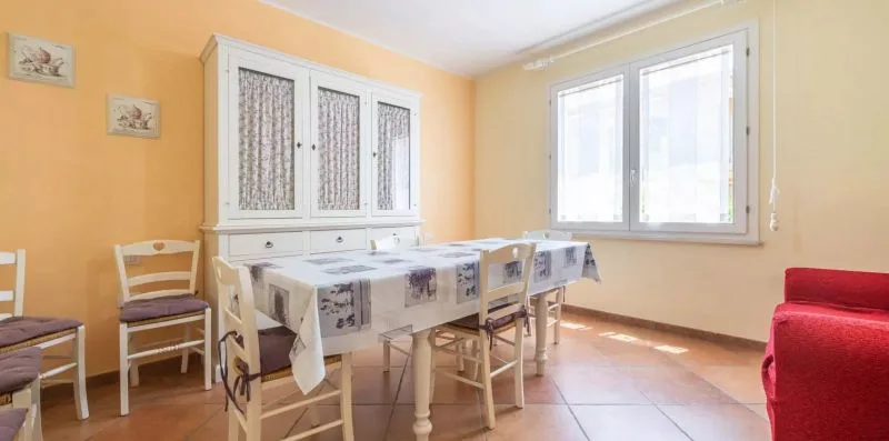 A dining area with a table and chairs beside large windows.