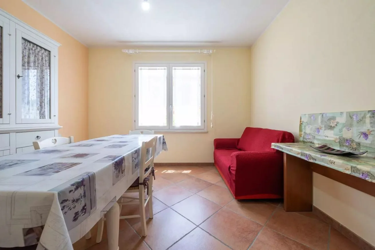 Comedor con una mesa y sillas junto a un sofá rojo.