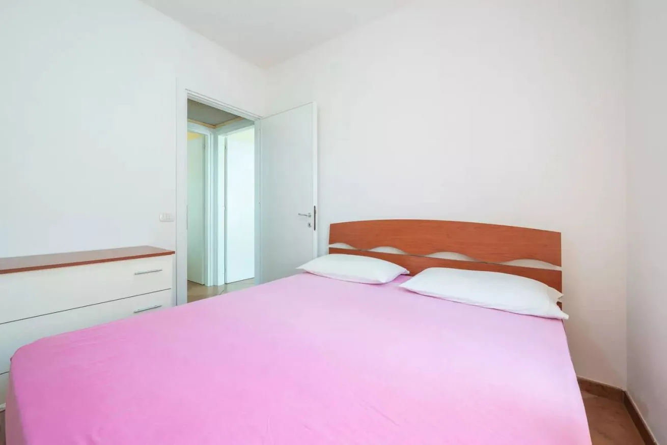 Un dormitorio con una cama cubierta con una colcha rosa.