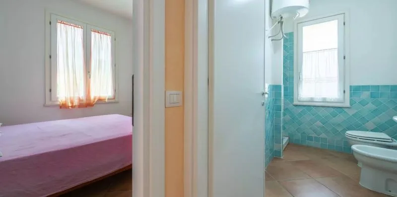 Un dormitorio con una cama junto a un baño con paredes de azulejos turquesa.