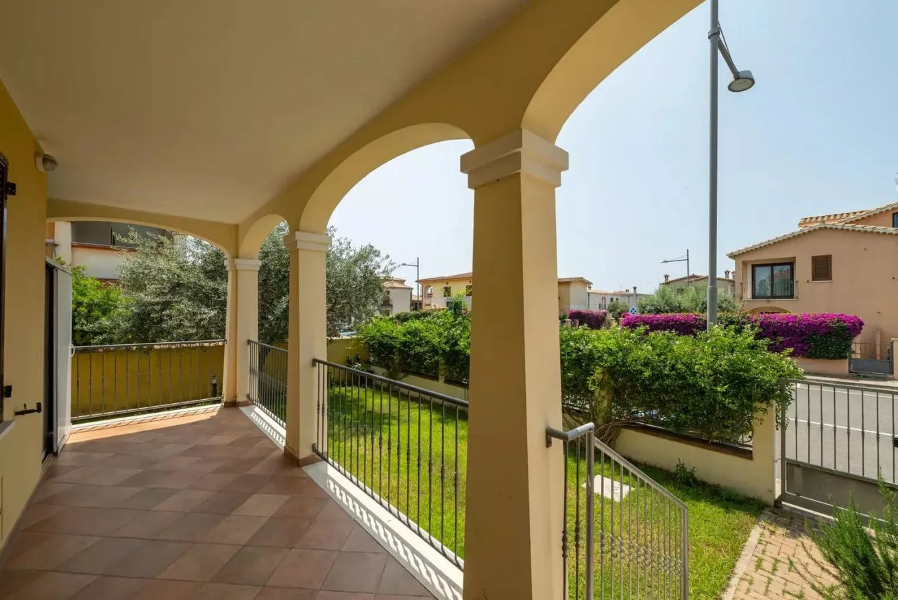 Una terraza exterior cubierta con arcos da a un pequeño jardín.