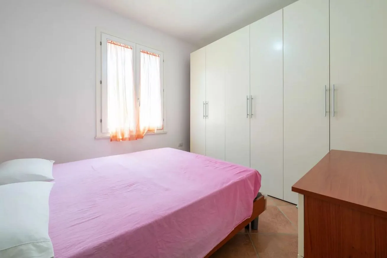 Un dormitorio con una cama, un armario y un escritorio de madera.