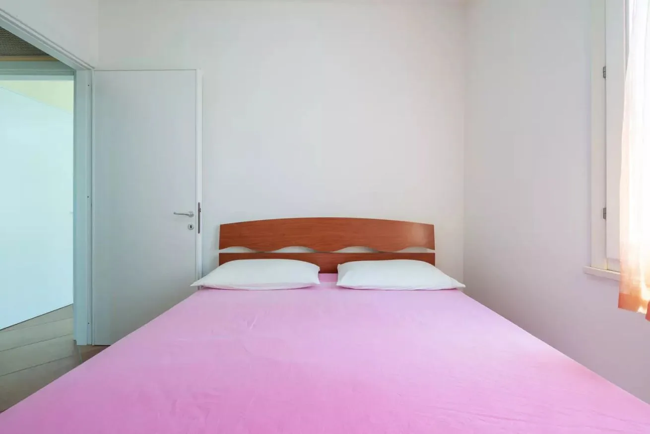 Un dormitorio con una cama cubierta con ropa de cama rosa y un cabecero de madera.