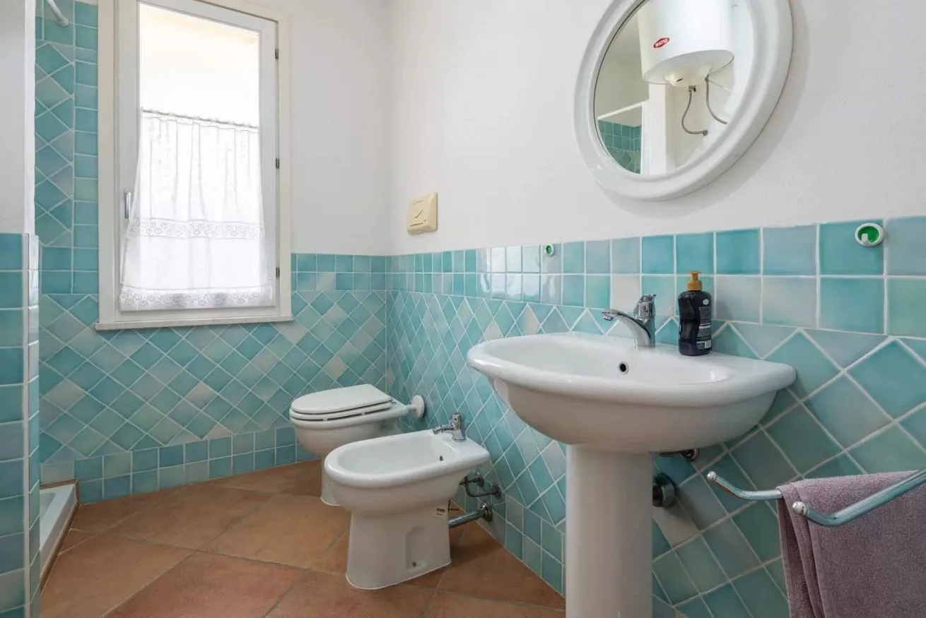 Un baño alicatado con lavabo de pedestal, inodoro y bidé.