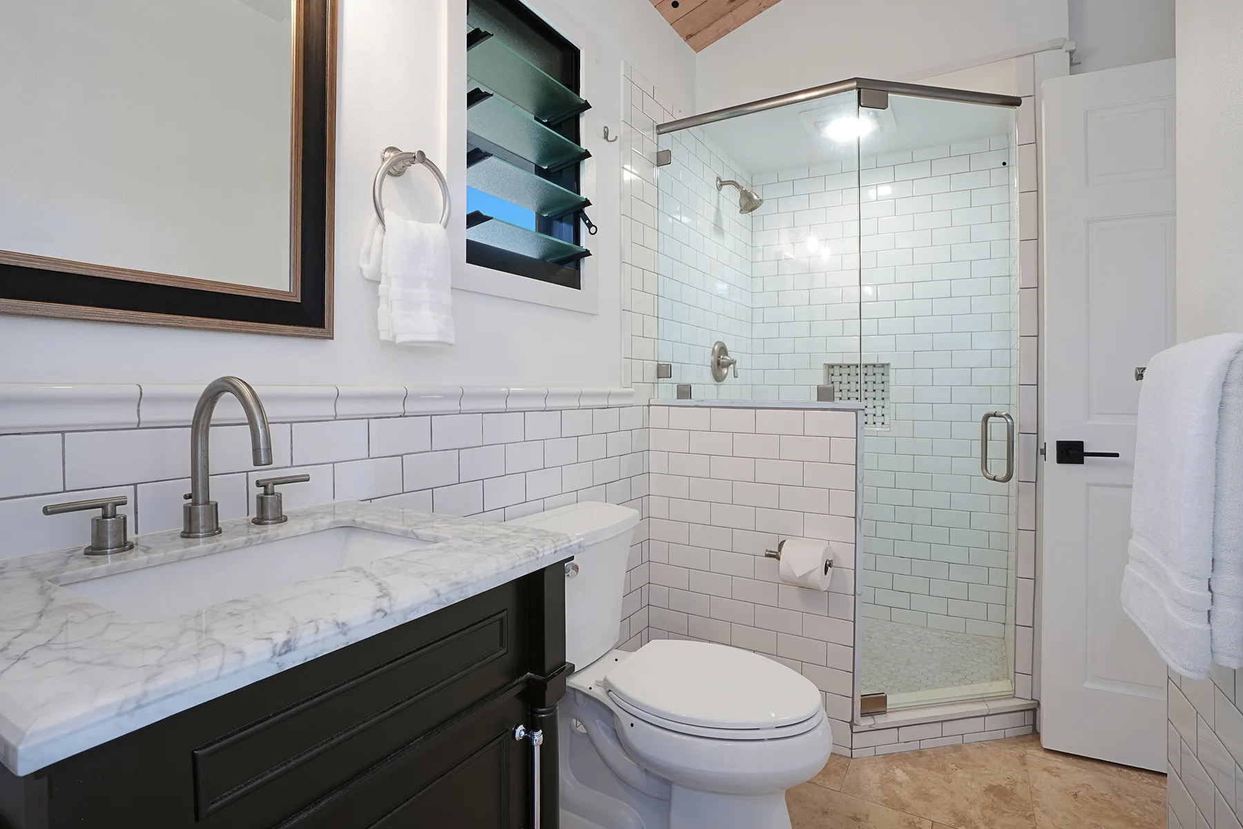 A bright bathroom with a tiled shower, vanity, and toilet.