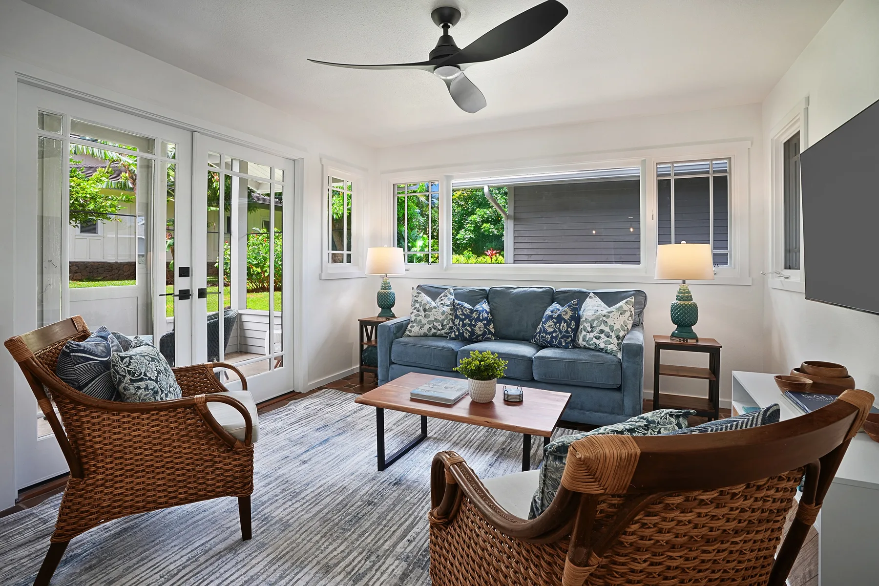A bright living room with a sofa, woven seating, and a coffee table.