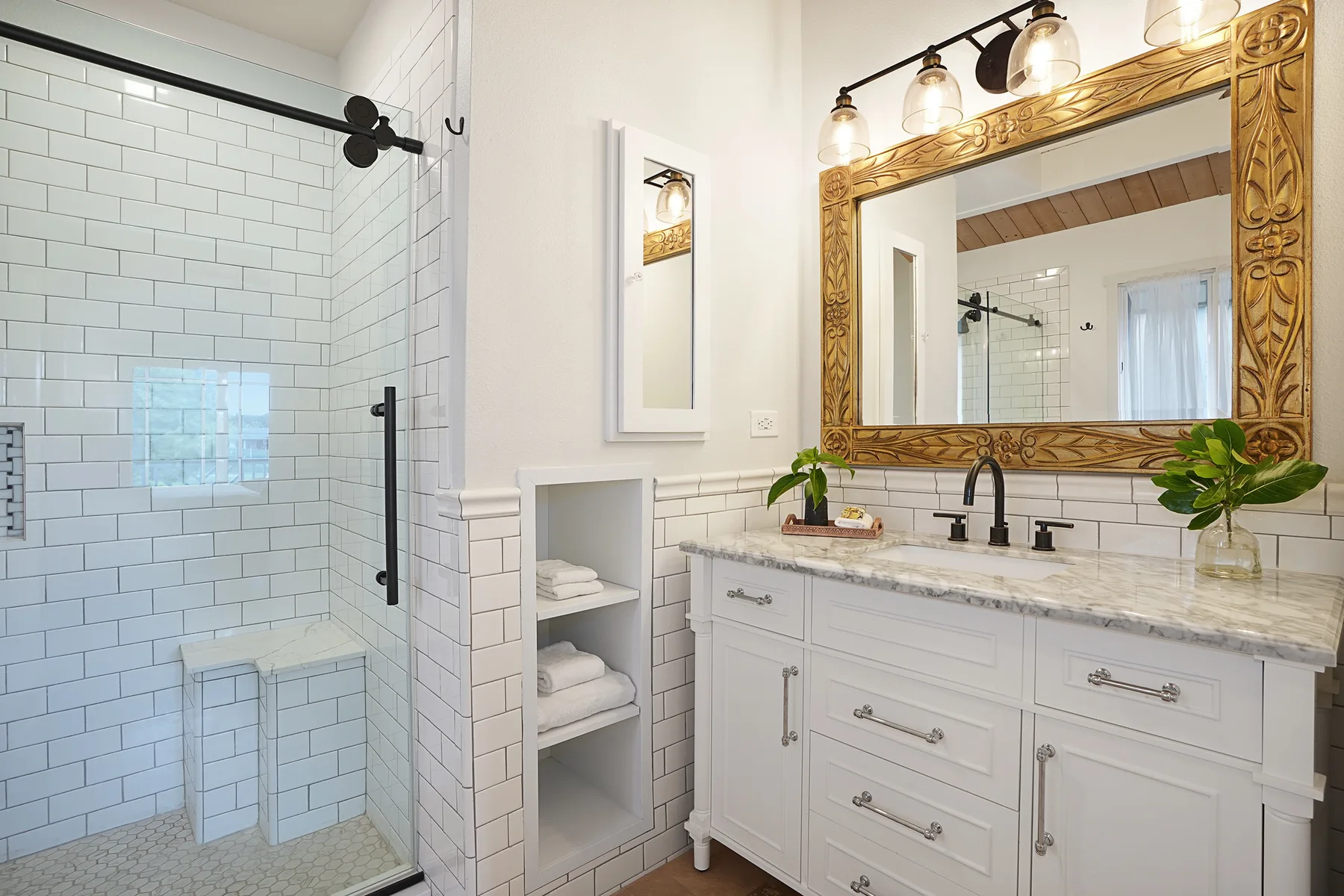 A bright bathroom features a glass shower and a white vanity beneath a large mirror.