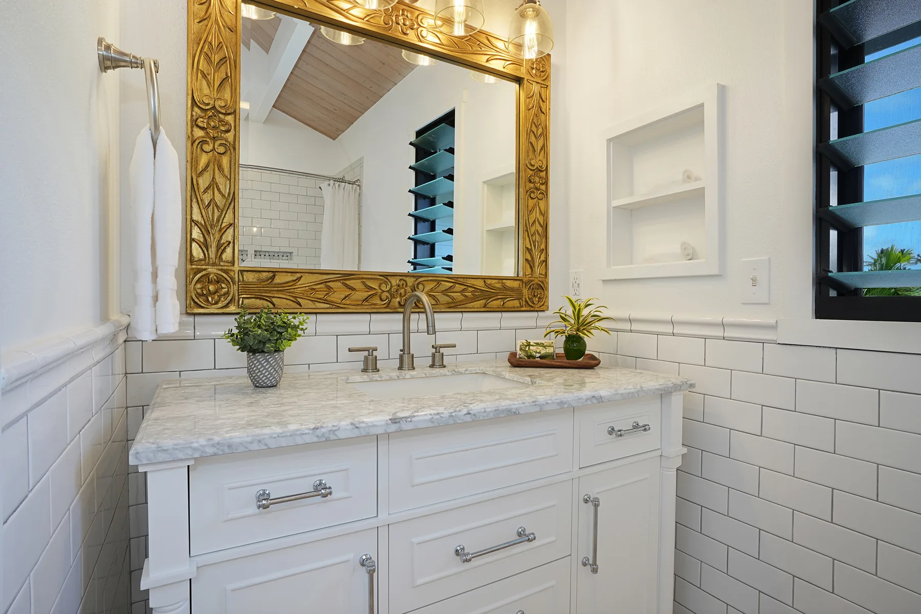 A bathroom vanity with a large framed mirror and tiled walls.